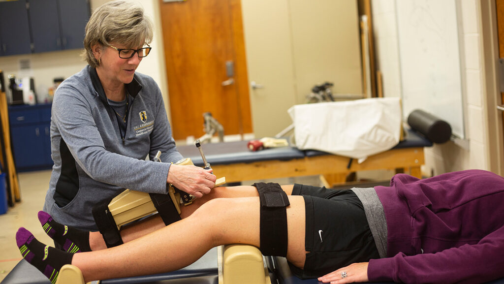 Sandra Schultz uses a device to measure knee laxity on a patient's knees