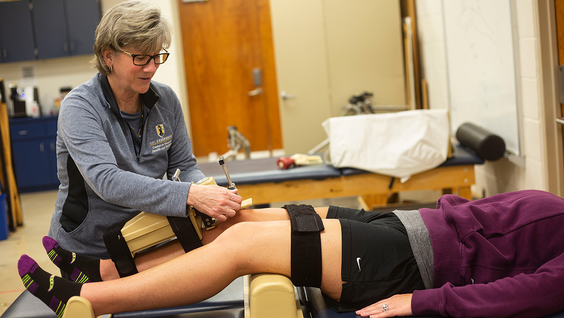Sandra Schultz uses a device to measure knee laxity on a patient's knees