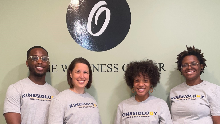 UNCG KIN in front of One Wellness Center Sign