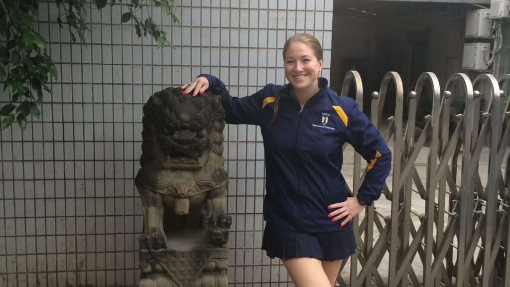 Jennifer Lichty posing by a statue of a Chinese guardian lion