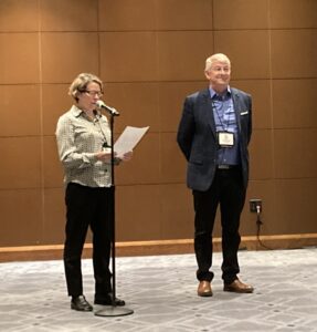 Two people standing in front of a wall.